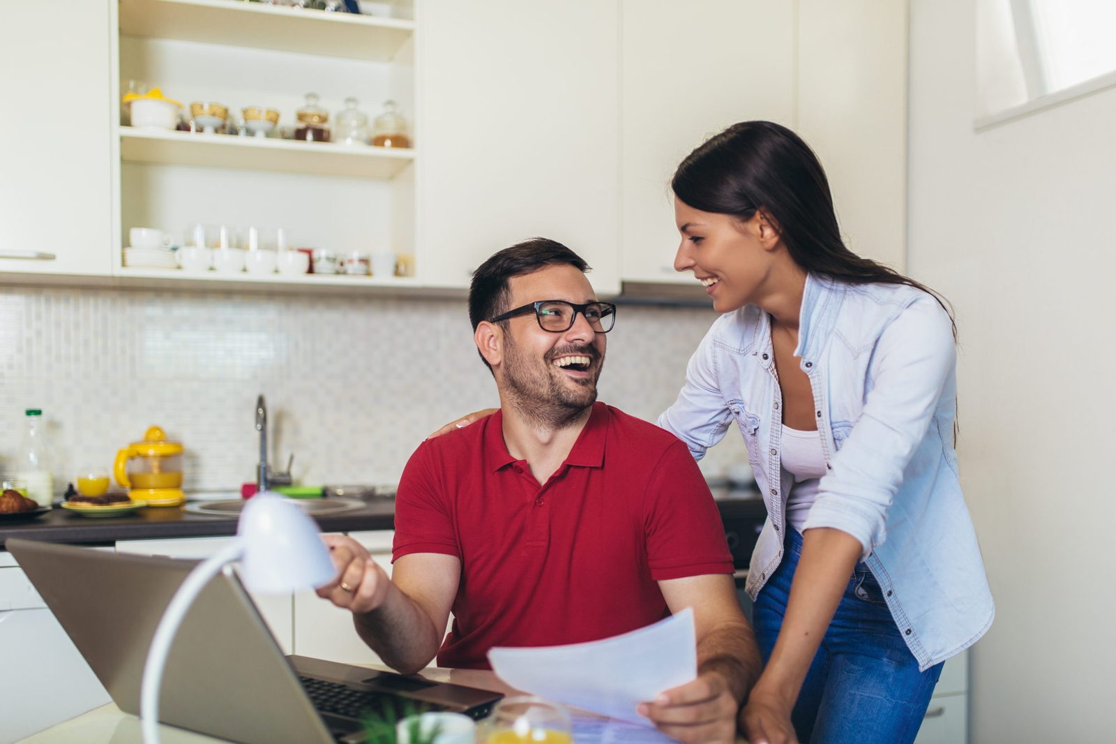 Una pareja de propietarios revisa sonriente el informe de su propiedad en la cocina de su casa